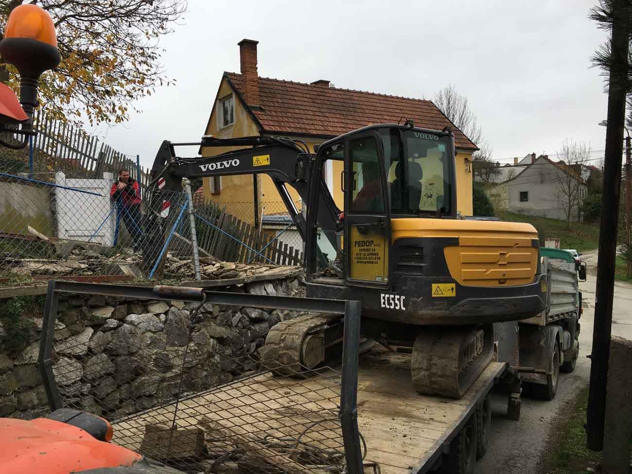 Rypadlo Volvo EC55C na podvalníku při dovozu na stavbu v obci