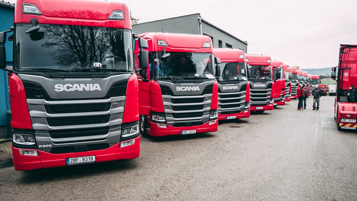 Řada červených tahačů Scania R500 PEDOP seřazených v areálu